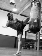 Person practicing martial arts with a punching bag in a gym.