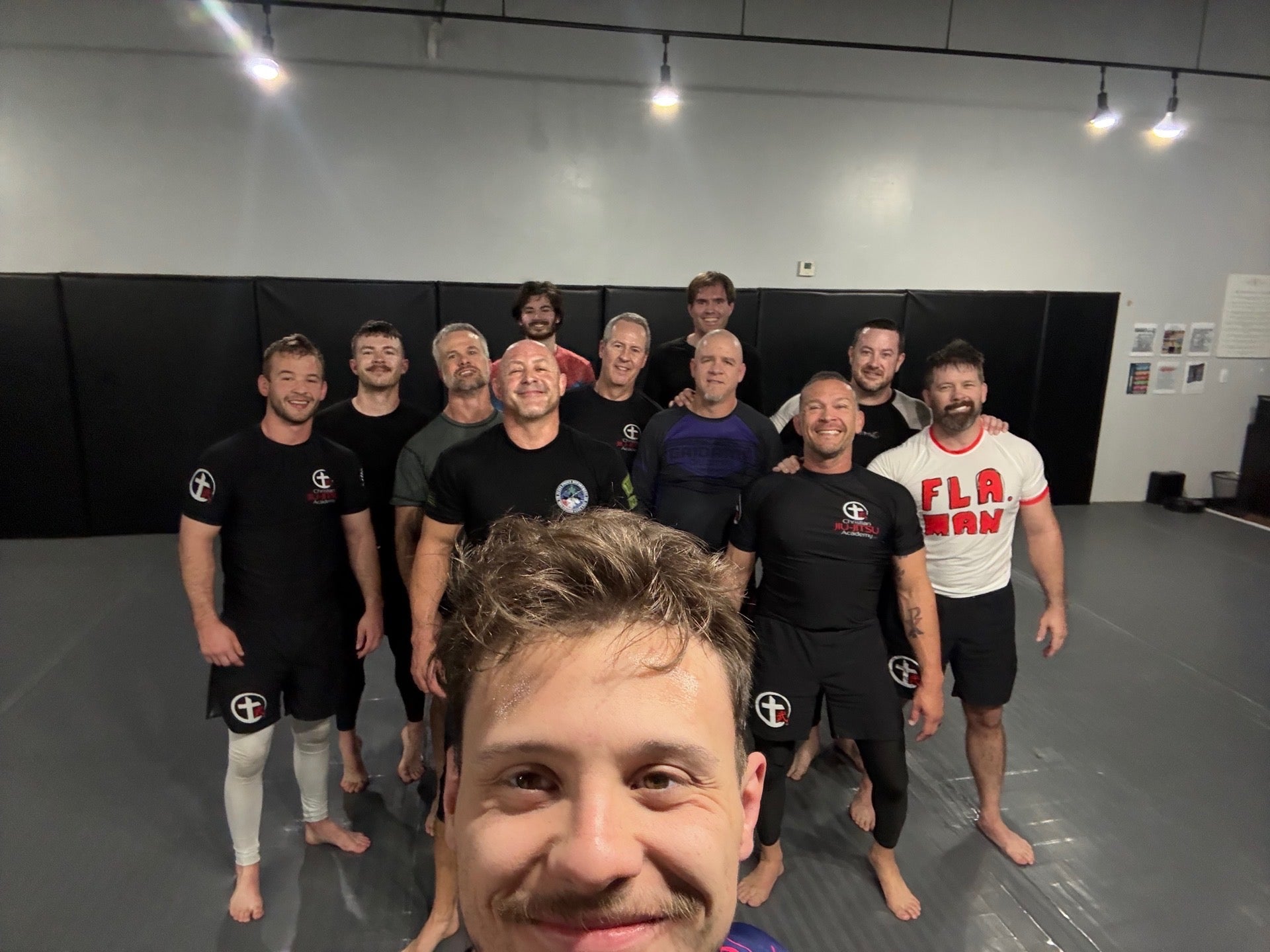 Group of men posing for a selfie in a martial arts training facility.