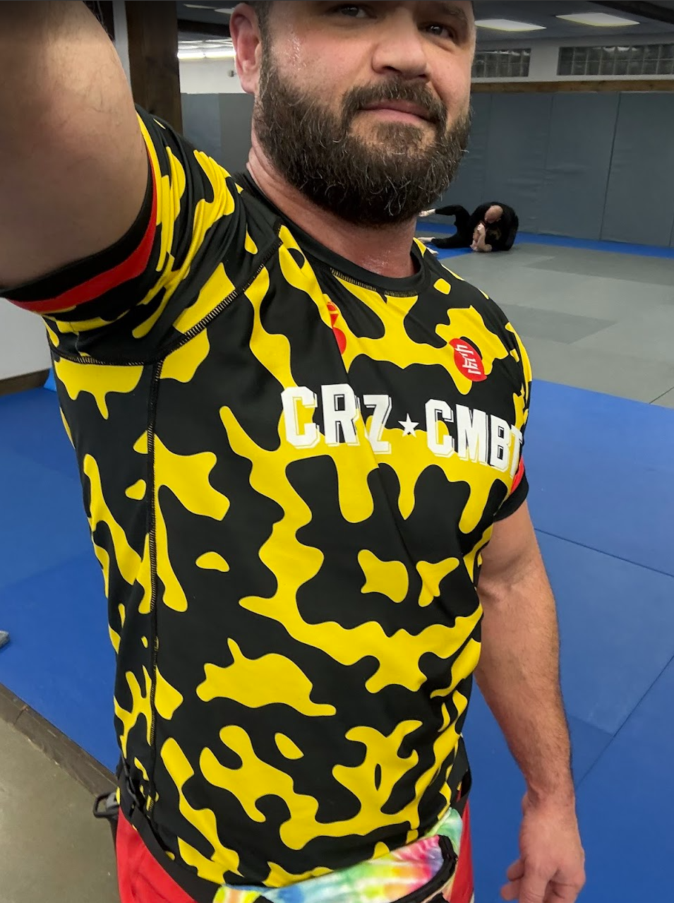 Person wearing a yellow and black camouflage sports jersey with visible branding in an indoor setting.