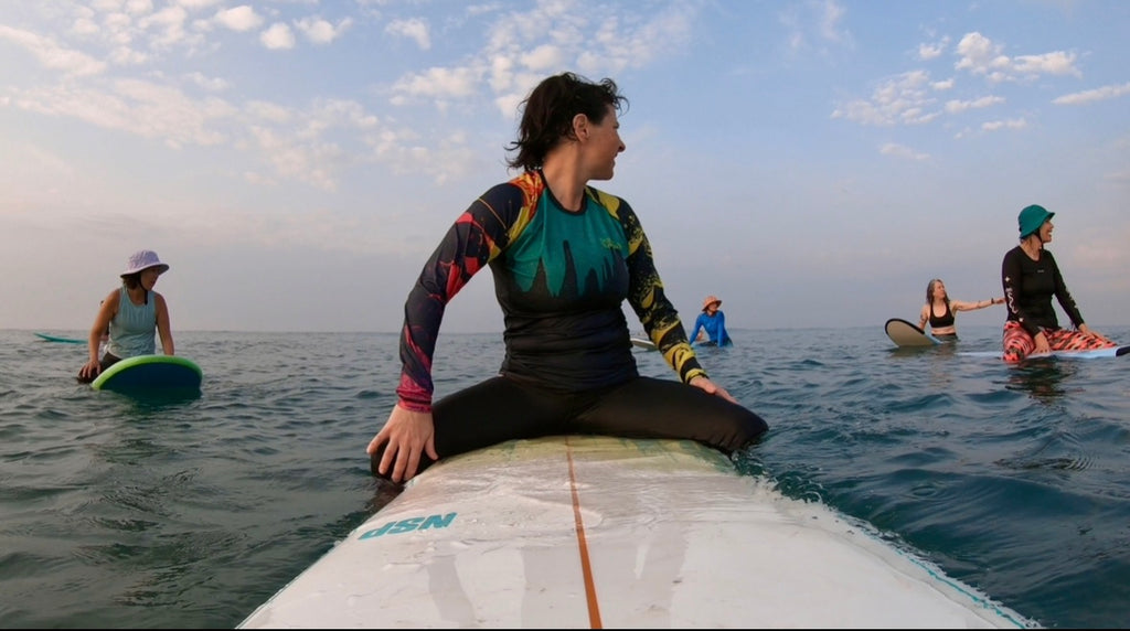 People on surfboards in the ocean with a clear sky