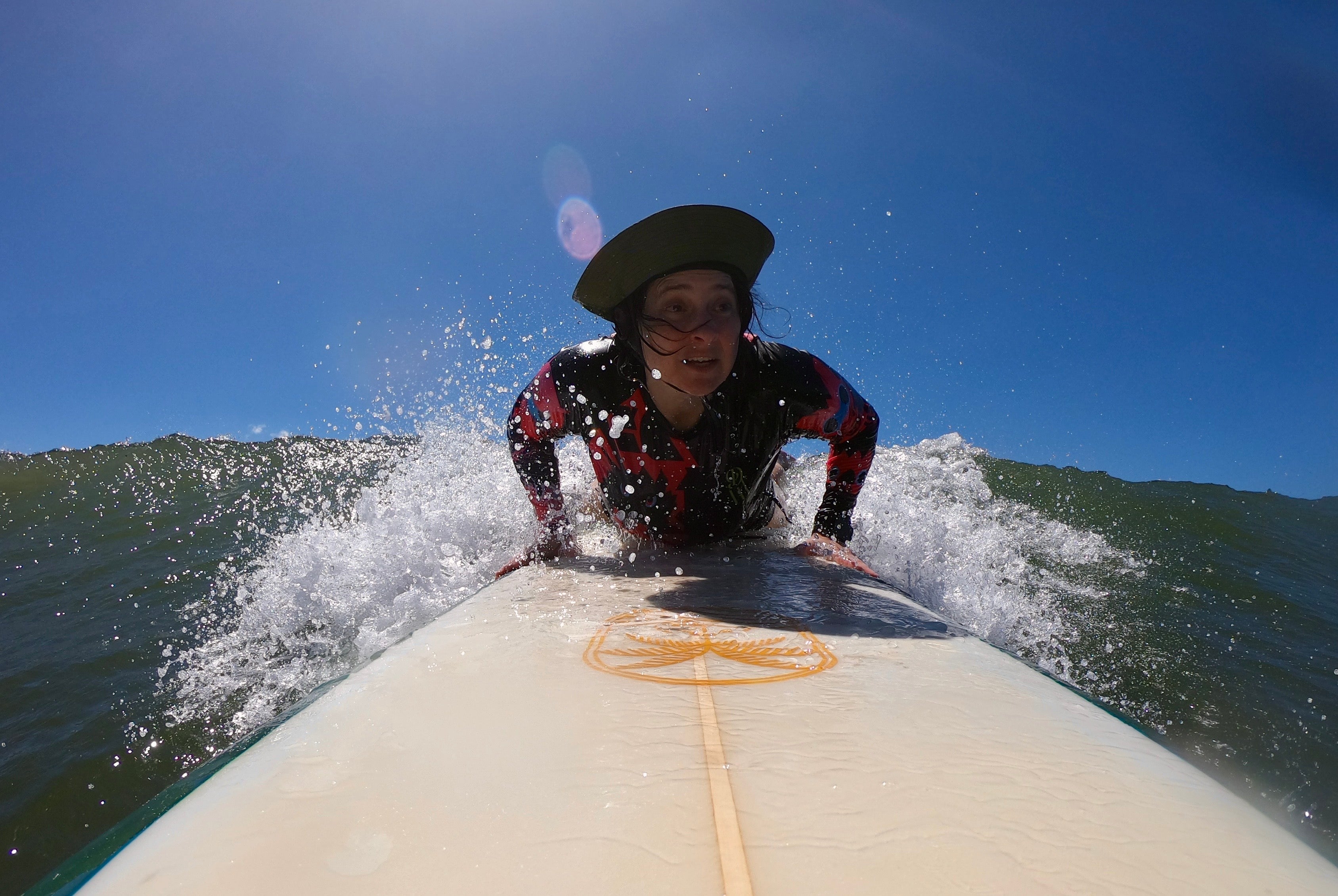 Person surfing on a wave with a clear blue sky