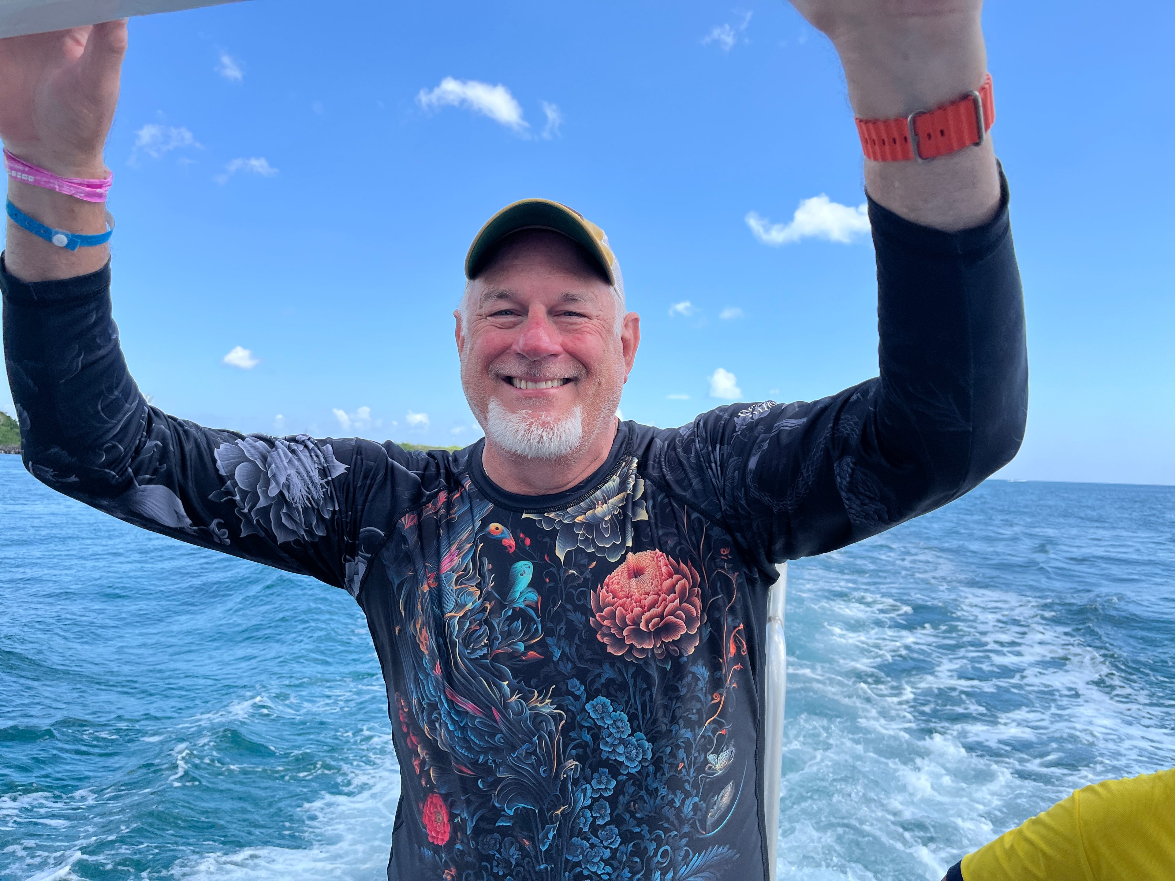 Man with arms raised on a boat with ocean and sky background